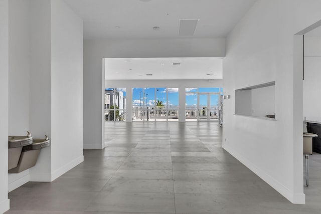 hallway with baseboards and concrete floors