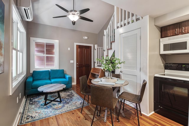 dining room with vaulted ceiling, a wall unit AC, ceiling fan, and light wood-type flooring