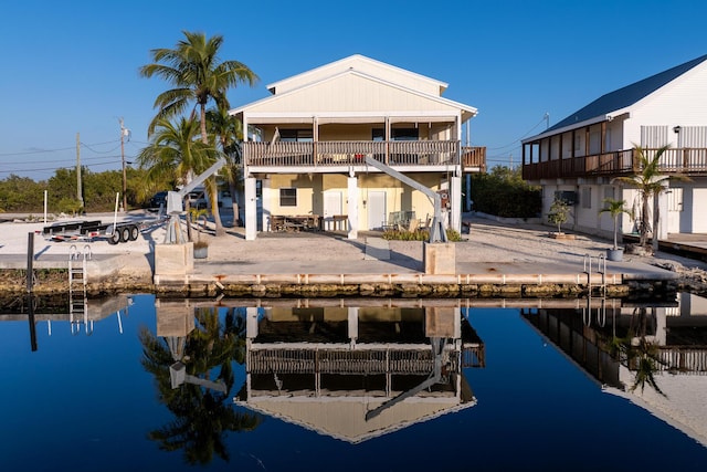 rear view of house with a balcony, a water view, and a patio area