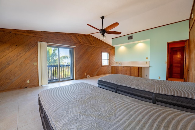 unfurnished bedroom featuring wood walls, vaulted ceiling, light tile patterned floors, ceiling fan, and access to exterior