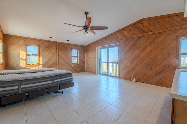 bedroom with light tile patterned flooring, vaulted ceiling, access to outside, wooden walls, and ceiling fan