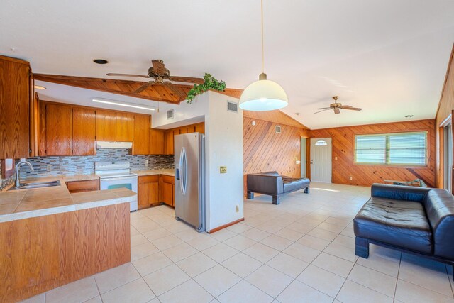 kitchen with electric stove, sink, stainless steel fridge, hanging light fixtures, and kitchen peninsula