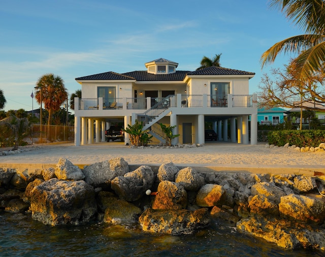 back of property with a carport, a water view, and french doors