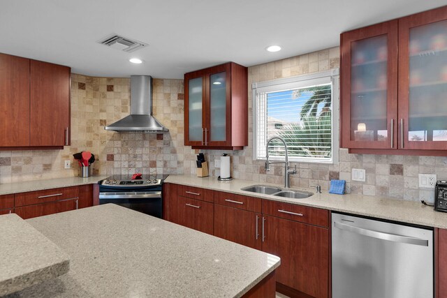 kitchen with wall chimney exhaust hood, appliances with stainless steel finishes, sink, and tasteful backsplash