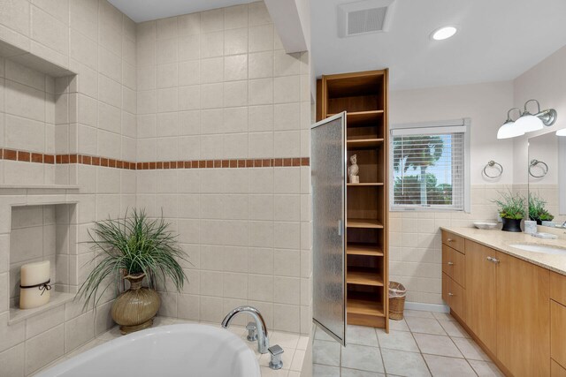 bathroom featuring tile walls, vanity, a washtub, and tile patterned floors