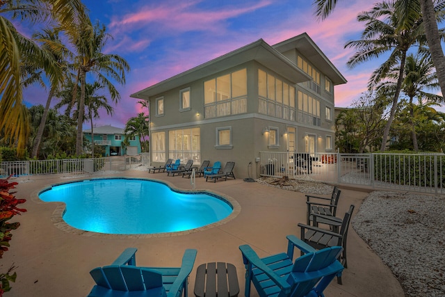 pool at dusk with a patio area