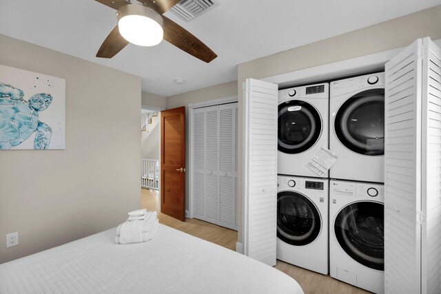 washroom featuring stacked washer / dryer, light wood-type flooring, and ceiling fan