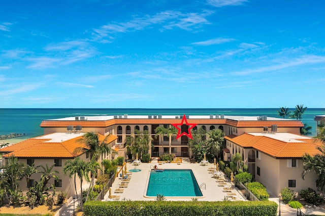 rear view of property with a community pool, a patio area, and a water view