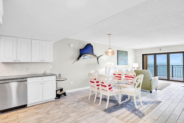 dining room featuring a water view, light hardwood / wood-style flooring, and a textured ceiling