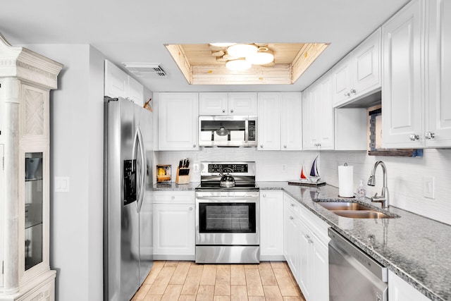 kitchen featuring appliances with stainless steel finishes, white cabinets, and a tray ceiling