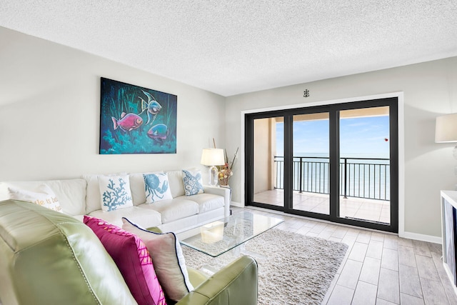 living room with a water view, a textured ceiling, and light hardwood / wood-style flooring