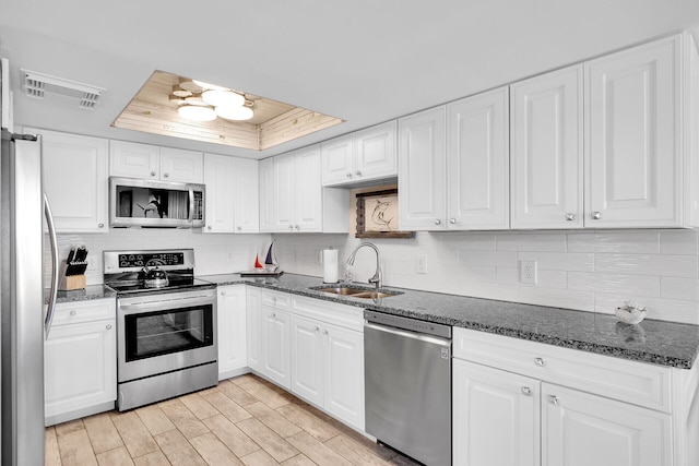 kitchen featuring sink, appliances with stainless steel finishes, white cabinetry, tasteful backsplash, and a tray ceiling