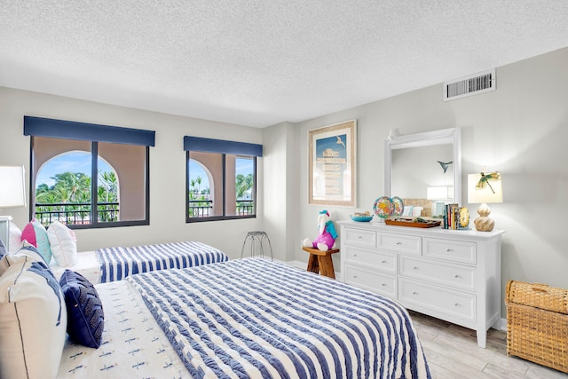 bedroom with a textured ceiling and light hardwood / wood-style floors