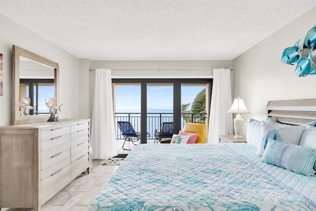 bedroom with a water view, a textured ceiling, and access to outside