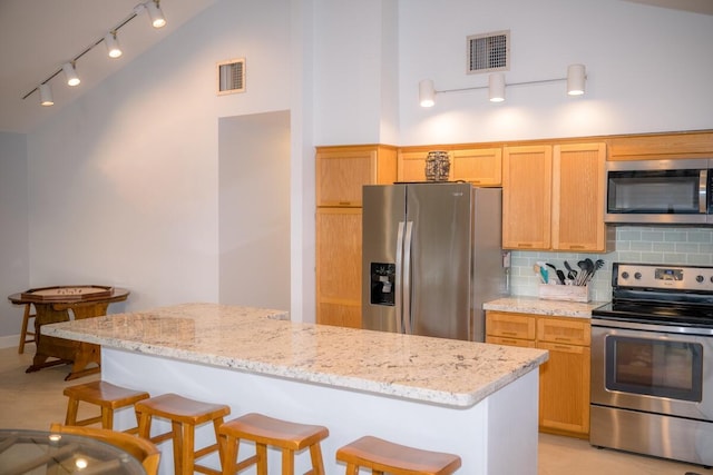 kitchen with stainless steel appliances, tasteful backsplash, a kitchen island, and a breakfast bar