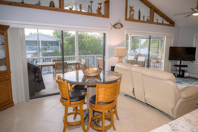 dining space with light tile patterned floors, ceiling fan, and high vaulted ceiling