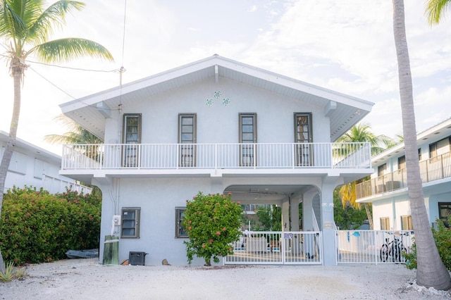 view of front of home featuring central air condition unit, fence, a balcony, and stucco siding