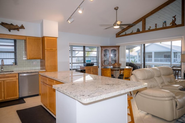 kitchen featuring lofted ceiling, a center island, a healthy amount of sunlight, stainless steel dishwasher, and a sink