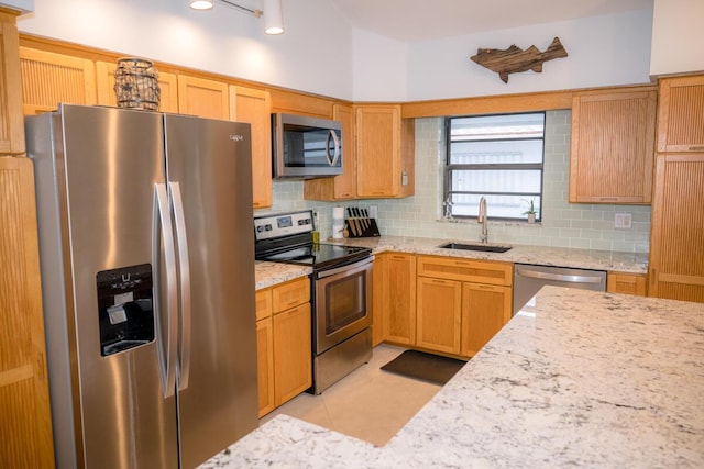 kitchen featuring tasteful backsplash, appliances with stainless steel finishes, light stone counters, a sink, and light tile patterned flooring