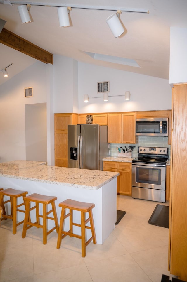 kitchen featuring visible vents, lofted ceiling with beams, appliances with stainless steel finishes, a breakfast bar, and light stone counters