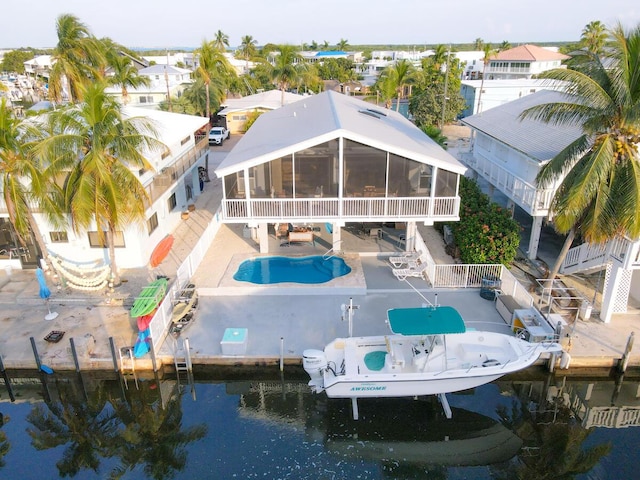 back of house with a sunroom, a patio area, a fenced backyard, and a community pool