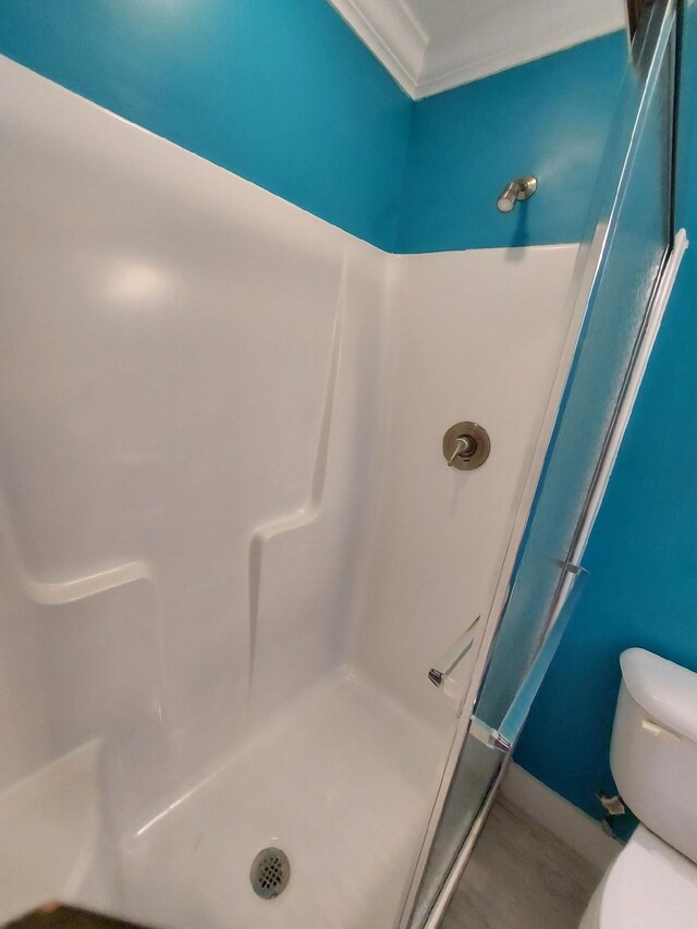 bathroom with a shower, crown molding, and toilet