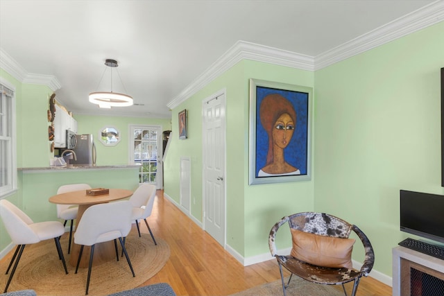 dining area featuring light wood-style flooring, baseboards, and crown molding