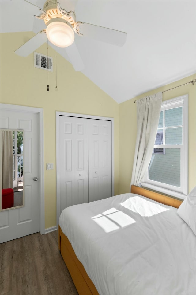 bedroom with lofted ceiling, a closet, visible vents, a ceiling fan, and wood finished floors