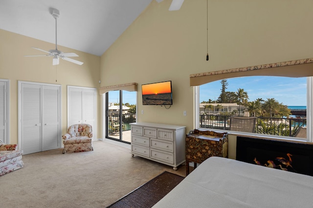 carpeted bedroom with a ceiling fan, access to outside, high vaulted ceiling, and multiple closets