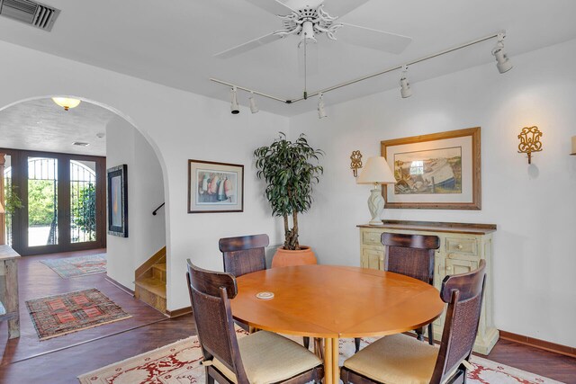 dining space with arched walkways, wood finished floors, visible vents, a ceiling fan, and stairway