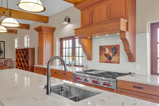 kitchen with tasteful backsplash, brown cabinetry, light stone counters, a sink, and beam ceiling
