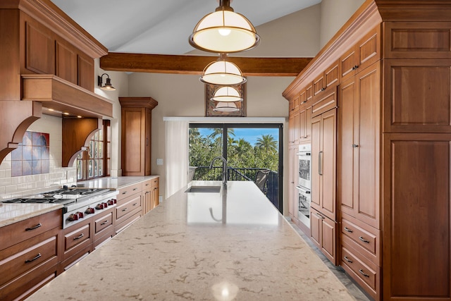 kitchen featuring tasteful backsplash, brown cabinets, light stone countertops, stainless steel appliances, and a sink