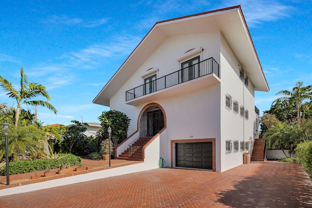 view of front of home featuring stairs, decorative driveway, a balcony, and stucco siding