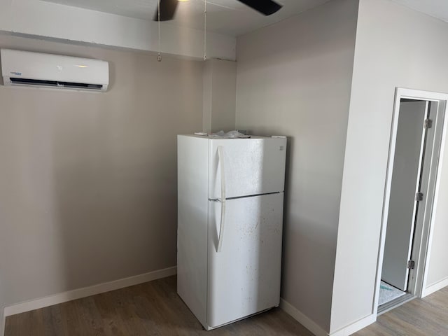 kitchen featuring a wall mounted air conditioner, wood finished floors, baseboards, and freestanding refrigerator
