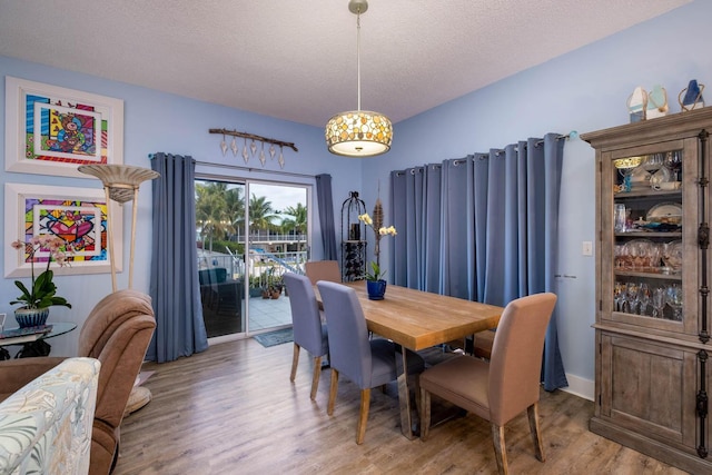 dining area with light wood-style floors and a textured ceiling