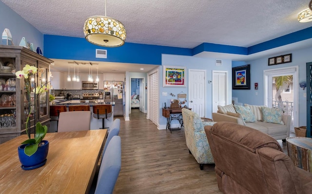 living area featuring visible vents, a textured ceiling, and dark wood-type flooring
