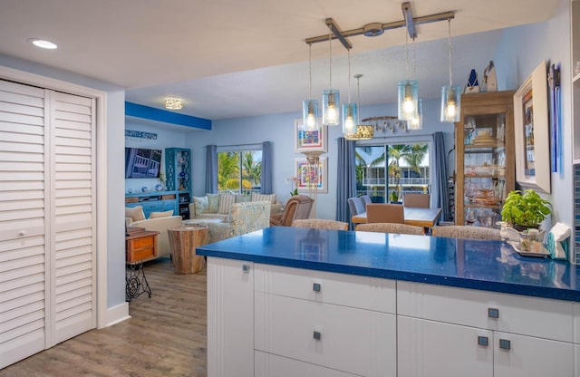 kitchen with dark countertops, white cabinetry, a wealth of natural light, and wood finished floors