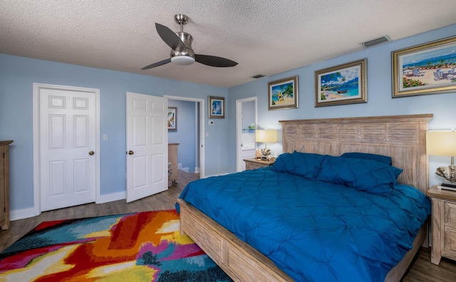 bedroom with visible vents, a textured ceiling, a ceiling fan, and wood finished floors