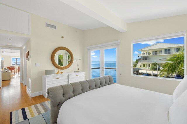 bedroom featuring a water view, vaulted ceiling with beams, access to outside, and light hardwood / wood-style floors