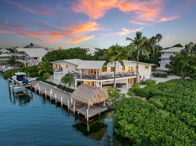 back house at dusk with a balcony and a water view