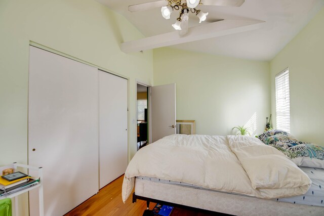 bedroom featuring vaulted ceiling with beams, hardwood / wood-style floors, ceiling fan, and a closet