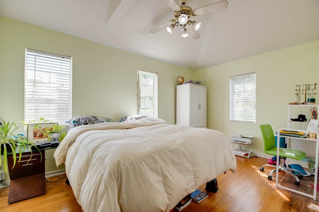 bedroom with ceiling fan, lofted ceiling, and light wood-type flooring