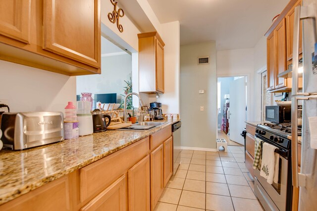 kitchen with sink, light stone counters, light brown cabinets, light tile patterned floors, and stainless steel appliances