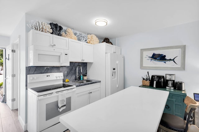 kitchen with sink, white appliances, white cabinetry, backsplash, and a kitchen island