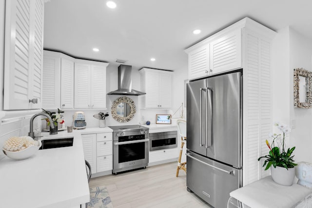 kitchen featuring white cabinetry, wall chimney range hood, sink, and premium appliances