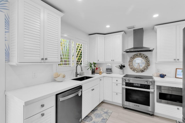 kitchen featuring white cabinetry, sink, stainless steel appliances, and wall chimney exhaust hood