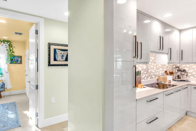 kitchen with black electric cooktop, light tile patterned floors, decorative backsplash, and white cabinets