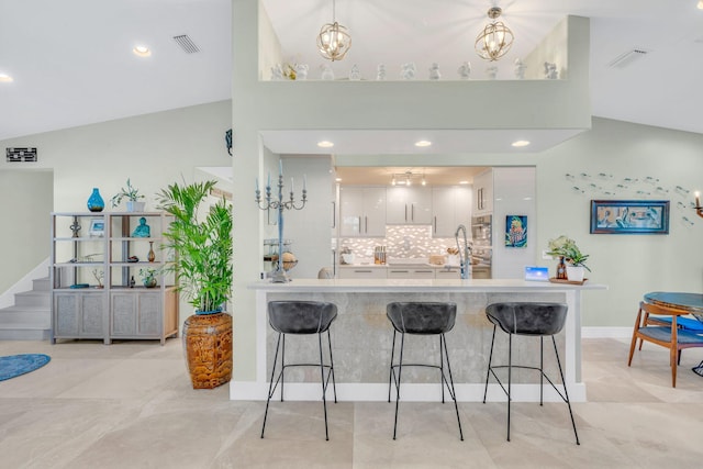 kitchen featuring white cabinetry, a kitchen bar, kitchen peninsula, and a notable chandelier