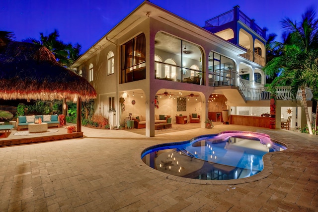 pool at night featuring a gazebo, ceiling fan, an outdoor hangout area, and a patio