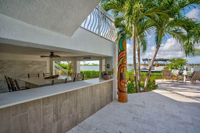 view of patio with a water view and ceiling fan